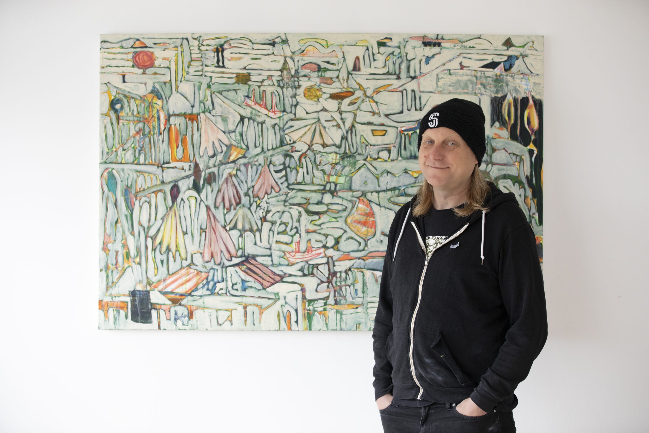 Artist Gordon Dalton stands with his abstract canvas painting